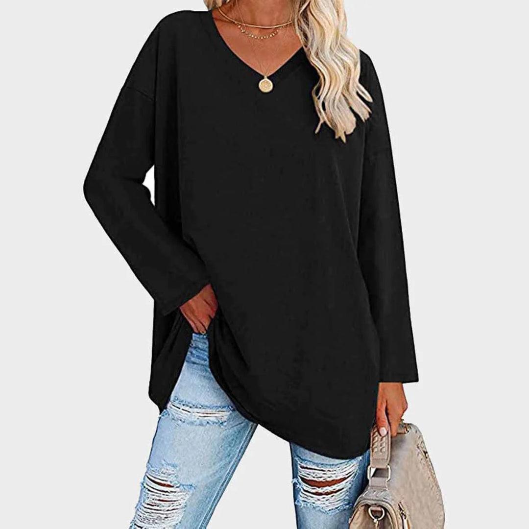 Kvinne i himmelblå genser med V-hals, slitte jeans og beige veske. Perfekt for casual mote og vårantrekk. Trendy og komfortabel stil.